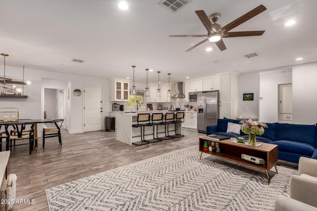 living room with ceiling fan, sink, and light wood-type flooring