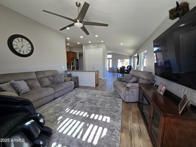 living area with a ceiling fan, visible vents, light wood-style flooring, recessed lighting, and vaulted ceiling