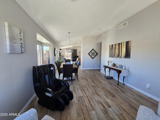 interior space with visible vents, baseboards, wood finished floors, and vaulted ceiling