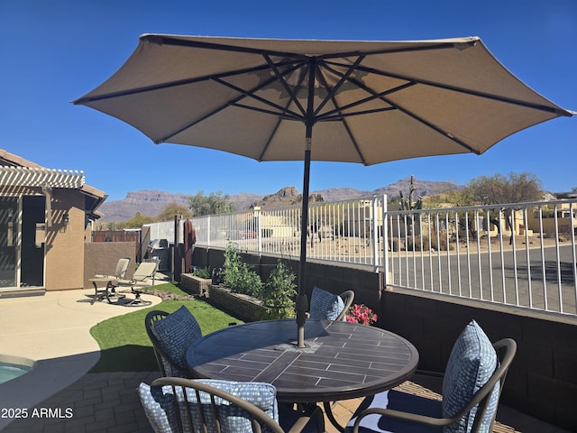 view of patio / terrace featuring a mountain view, a pergola, outdoor dining area, and a fenced backyard