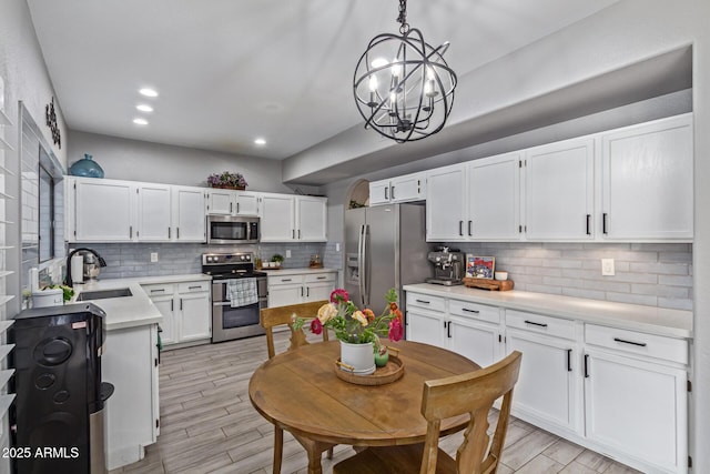 1231 W Mediterranean Dr, Gilbert, AZ 85233 - kitchen featuring stainless steel appliances, a sink, a chandelier, tasteful backsplash, and light countertops