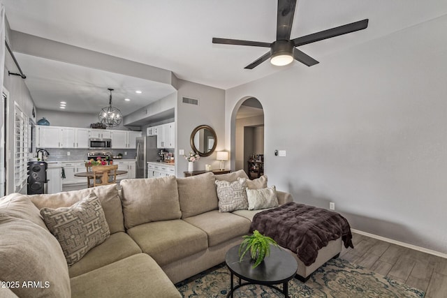 1231 W Mediterranean Dr, Gilbert, AZ 85233 - living room with arched walkways, wood finished floors, a ceiling fan, a chandelier, and baseboards