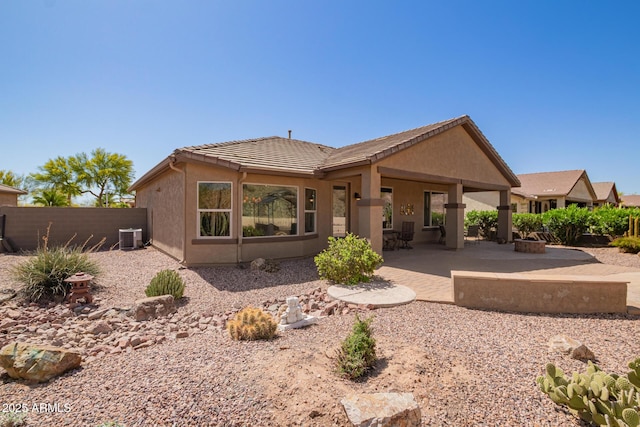 rear view of house with central AC unit, a tile roof, a patio, and stucco siding