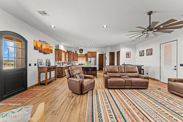 living room with sink, light wood-type flooring, and ceiling fan