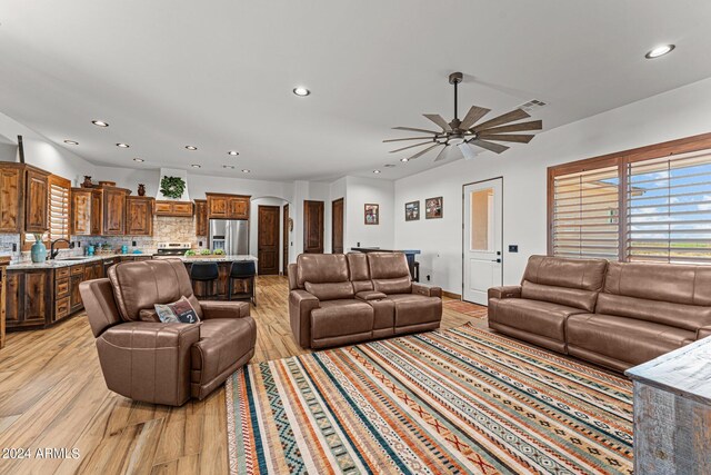 living room featuring sink, ceiling fan, and light hardwood / wood-style floors