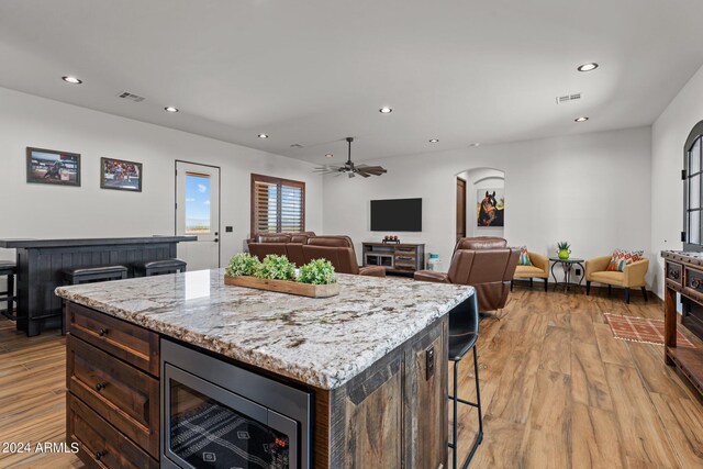 kitchen with a center island, ceiling fan, stainless steel microwave, and light hardwood / wood-style floors