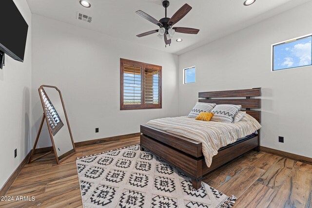 bedroom with hardwood / wood-style flooring, multiple windows, and ceiling fan