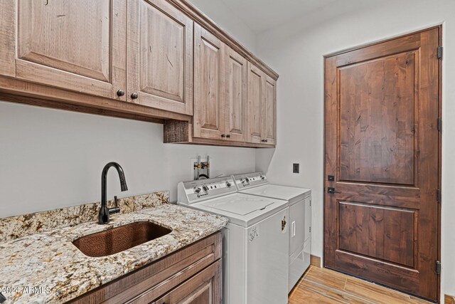 clothes washing area featuring sink, cabinets, and washer and dryer