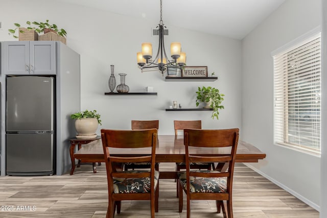 dining space featuring vaulted ceiling, a notable chandelier, and light wood-type flooring