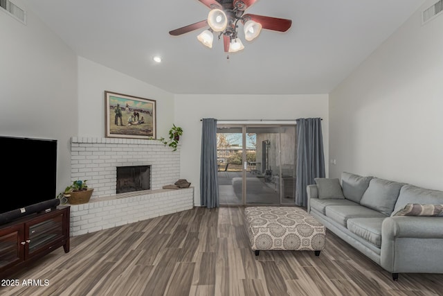 living room featuring a brick fireplace, hardwood / wood-style floors, and ceiling fan