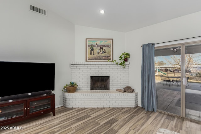 living room featuring vaulted ceiling, wood-type flooring, and a fireplace