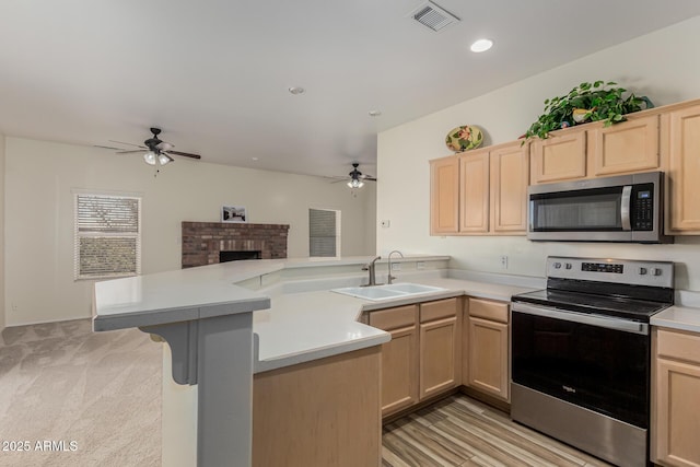 kitchen featuring light brown cabinetry, sink, kitchen peninsula, and appliances with stainless steel finishes