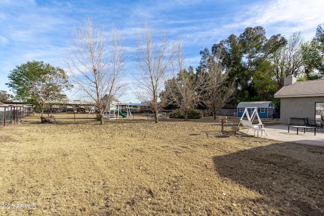 view of yard featuring a storage shed, a patio, and a playground