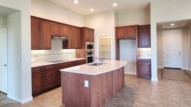 kitchen featuring stainless steel appliances, sink, backsplash, and a kitchen island with sink