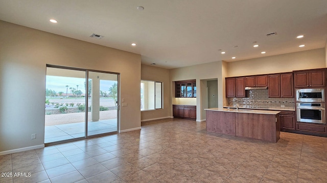 kitchen featuring backsplash, sink, a kitchen island with sink, stainless steel appliances, and light tile patterned floors