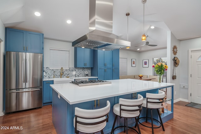 kitchen with stainless steel appliances, blue cabinets, island range hood, and hanging light fixtures