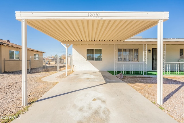 view of front of home with covered porch, fence, a carport, and brick siding