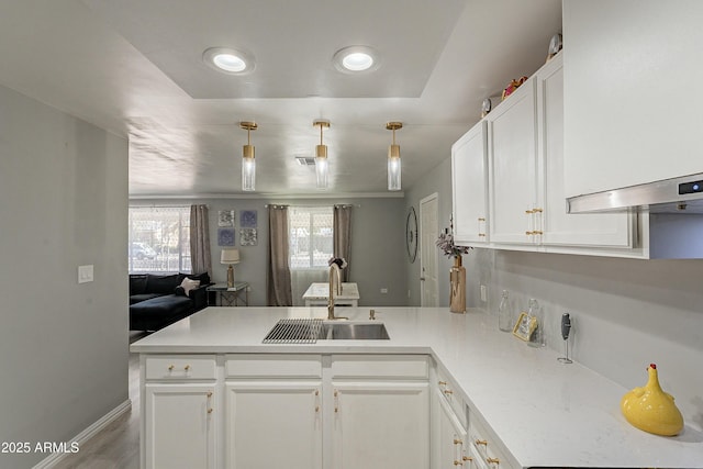 kitchen featuring light countertops, white cabinets, a sink, and a peninsula