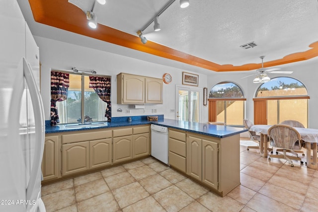 kitchen with a textured ceiling, a tray ceiling, kitchen peninsula, and white appliances