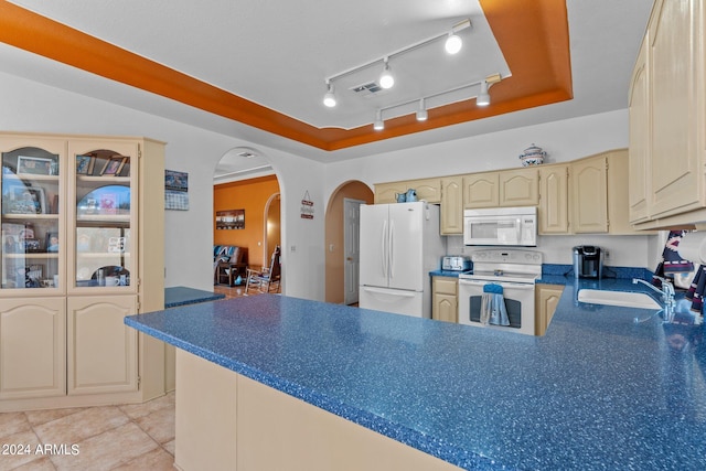 kitchen with a tray ceiling, white appliances, sink, and light tile patterned floors