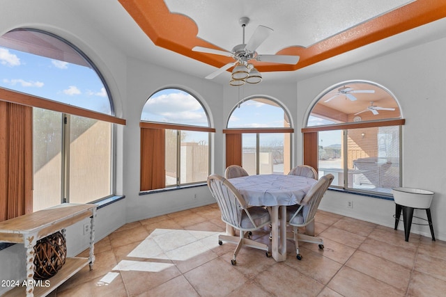 tiled dining area with a tray ceiling and ceiling fan