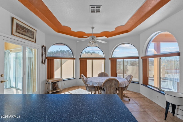 tiled dining area featuring plenty of natural light and a tray ceiling