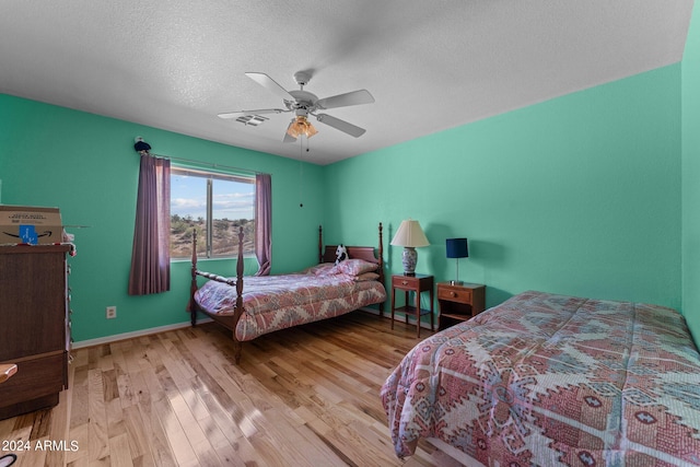 bedroom with light hardwood / wood-style floors, a textured ceiling, and ceiling fan