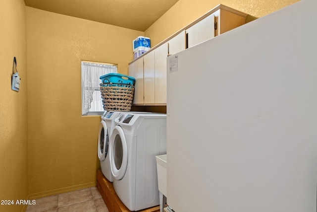 laundry room featuring light tile patterned flooring, a textured ceiling, and washing machine and clothes dryer