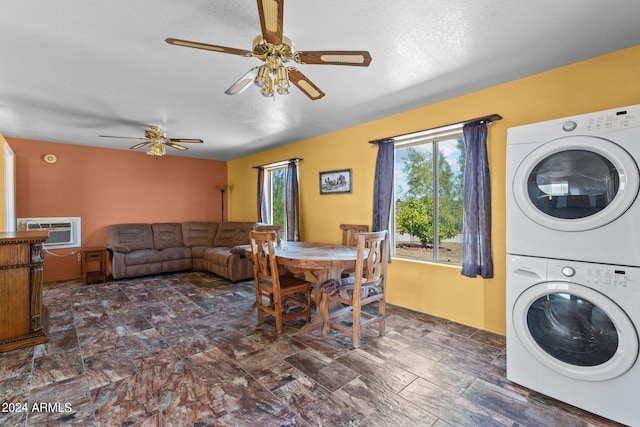 clothes washing area with ceiling fan, a textured ceiling, stacked washer and dryer, and a wall unit AC