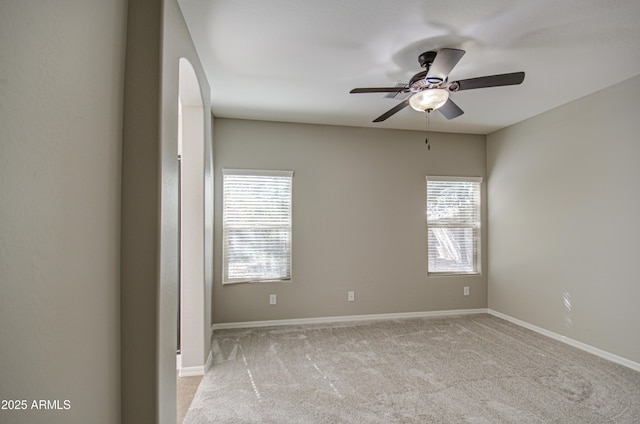 carpeted empty room featuring ceiling fan and baseboards