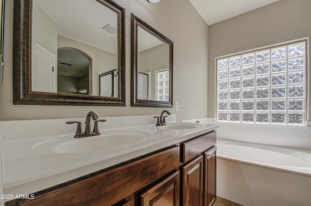 bathroom with a garden tub, double vanity, a sink, and visible vents