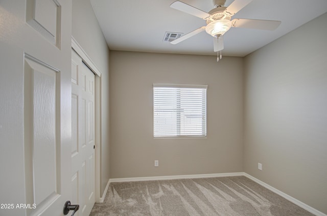 carpeted empty room with baseboards, visible vents, and ceiling fan