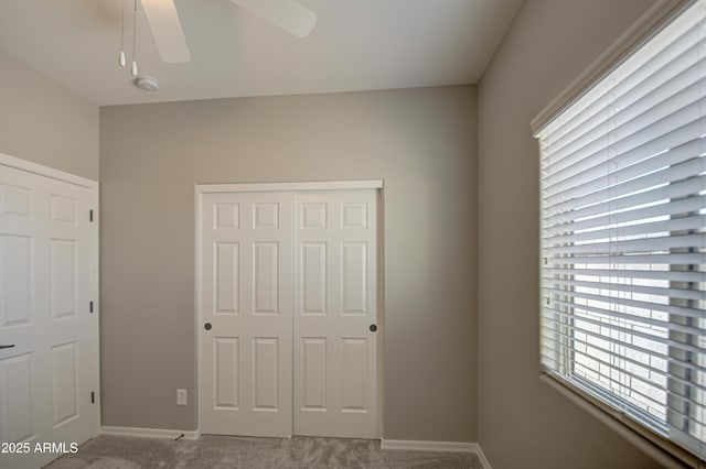 unfurnished bedroom with carpet floors, a ceiling fan, baseboards, and a closet