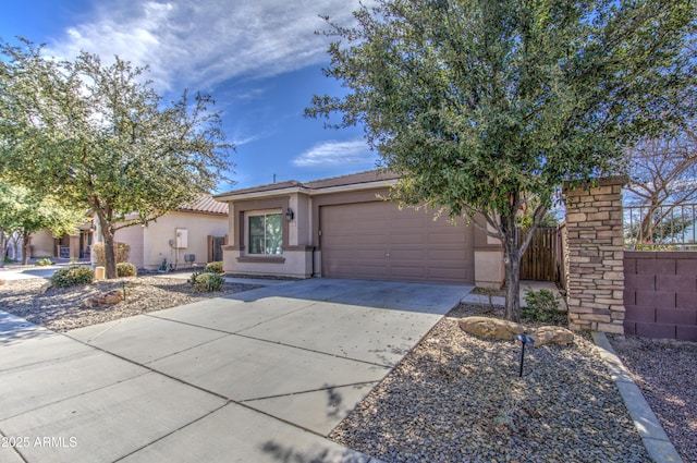 view of front facade with driveway, a tiled roof, an attached garage, fence, and stucco siding