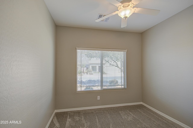 carpeted spare room with visible vents, baseboards, and a ceiling fan