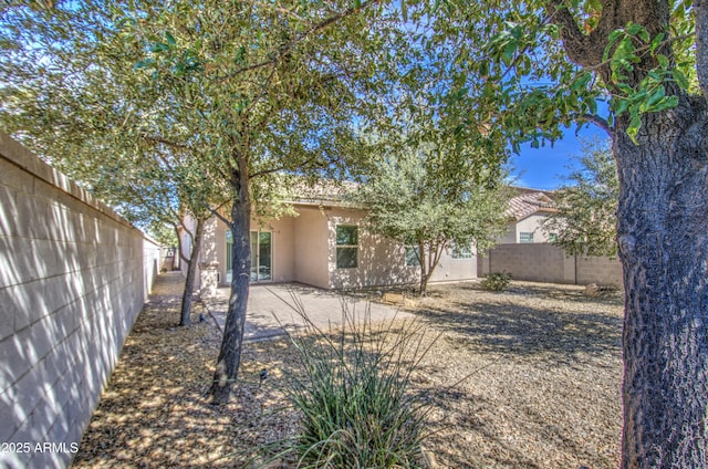 back of property with a fenced backyard, a patio, and stucco siding