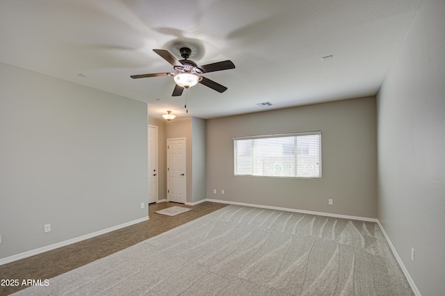 carpeted empty room featuring a ceiling fan, visible vents, and baseboards