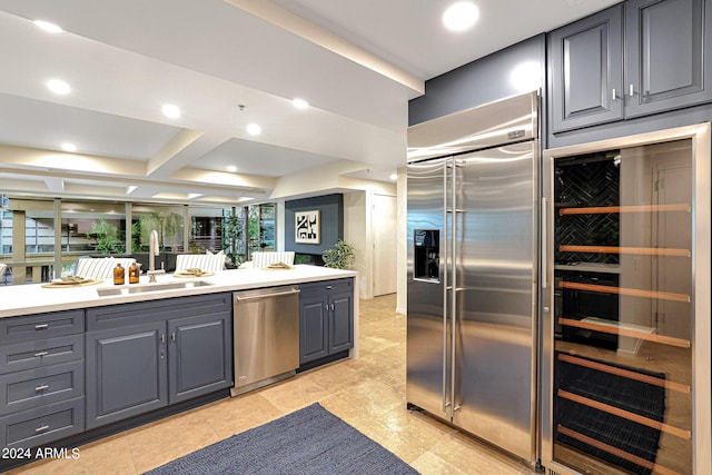 kitchen featuring gray cabinets, a sink, stainless steel appliances, wine cooler, and light countertops