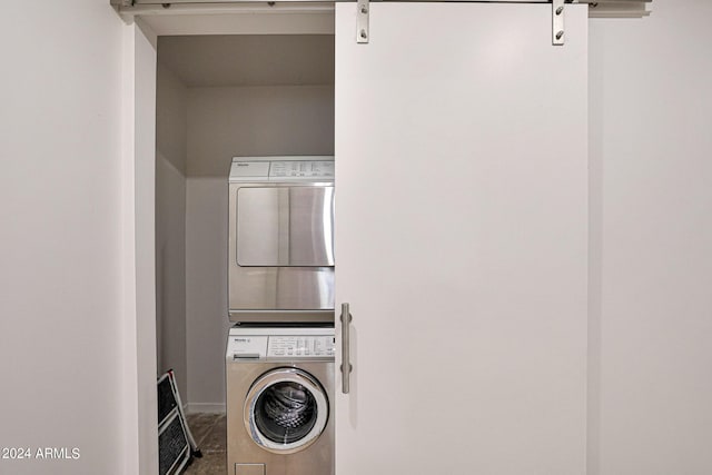 clothes washing area featuring laundry area, stacked washer / drying machine, and a barn door