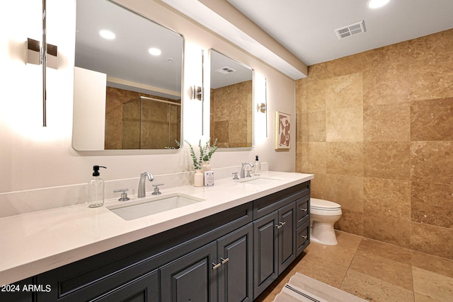 bathroom with a tile shower, visible vents, toilet, and a sink