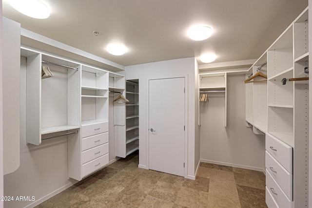 walk in closet featuring stone finish floor