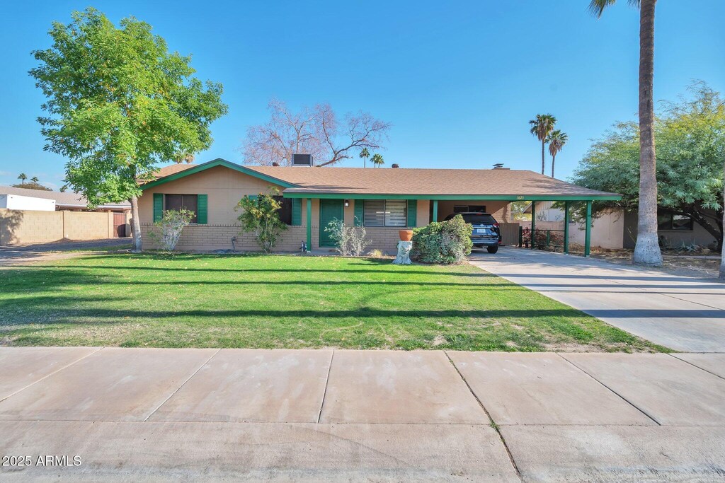 single story home featuring a front lawn and a carport