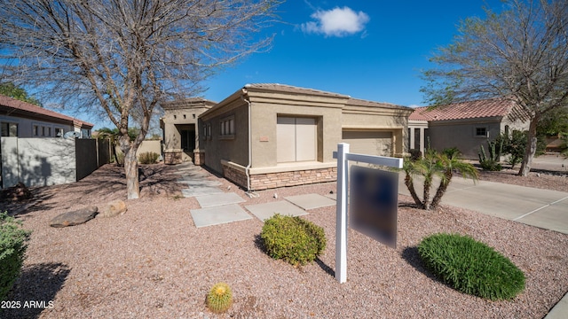 view of front facade with stucco siding, a tile roof, stone siding, fence, and a garage