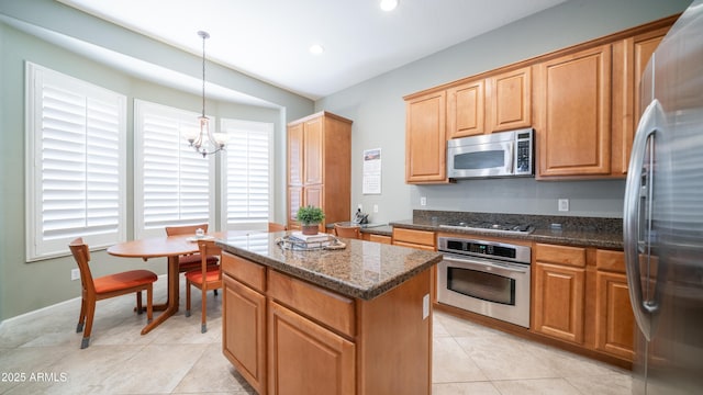 kitchen featuring a kitchen island, a chandelier, dark stone counters, light tile patterned floors, and appliances with stainless steel finishes