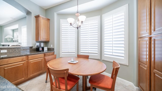 dining space featuring an inviting chandelier, light tile patterned floors, and baseboards