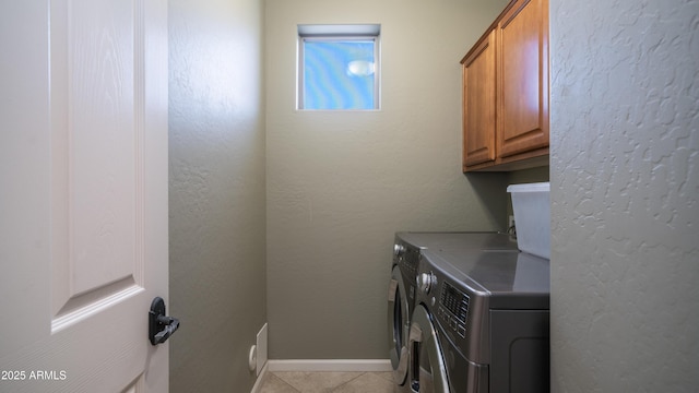 washroom featuring cabinet space, separate washer and dryer, light tile patterned floors, baseboards, and a textured wall