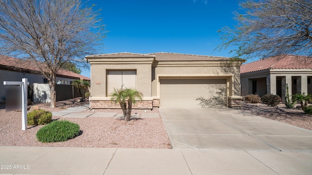 view of front of property featuring stucco siding, driveway, a tile roof, stone siding, and an attached garage