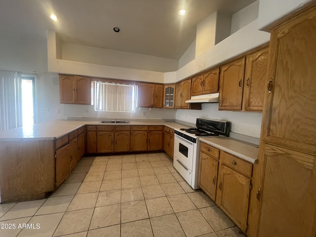 403 E 6th St, Douglas, AZ 85607 - kitchen with white stove, under cabinet range hood, a peninsula, brown cabinetry, and light countertops