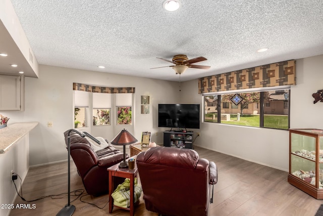 living area featuring recessed lighting, ceiling fan, a textured ceiling, and light wood-style flooring