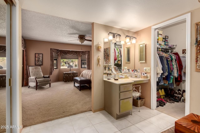 ensuite bathroom featuring vanity, connected bathroom, tile patterned floors, a ceiling fan, and a walk in closet